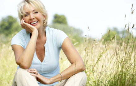 mature woman in field looing happy. How to be happier, improve mood