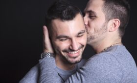 sexual orientation - two men embracing, one kissing the other on the cheek
