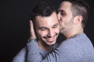 sexual orientation - two men embracing, one kissing the other on the cheek