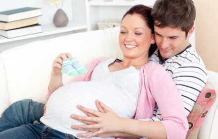 pregnancy mental health, pregnant woman being supported by male partner and looking at baby booties